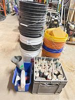 Stacked black, white and orange buckets alongside crate of caulking tubes and sponge