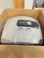 Water heater inside box showing front control panel and branding