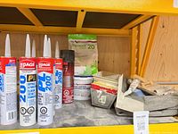 Tubes of adhesive, Sheetrock compounds, tools on shelf