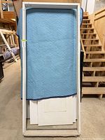 Full view of white interior door jamb leaning against padded blanket