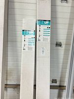 Both boxed poles leaning against wall showing front labels