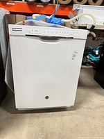 Full front view of white GE dishwasher with hoses attached