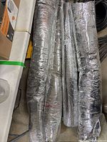 Stack of four insulated HVAC duct rolls with foil exterior