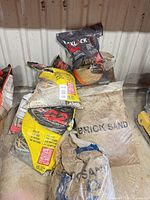 Stack of various sand bags including yellow Alliance G2 polymeric sand and Brick Sand
