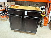 Front view of black kitchen base cabinet, doors closed