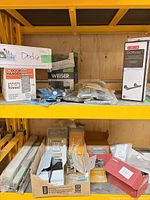 Two shelves showing boxed and packaged door hardware including OnGARD, Weiser, Delta Dorval, hinges