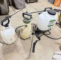 Overall view of three sprayers showing backpack unit and two handheld units with hoses and wands