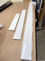 Three narrow white quartz slabs laid on workbench