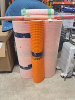 Front view showing two large pink rolls, one orange Ditra-XL roll and three smaller rolls