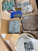 Top view showing multiple open containers of nails, screws, cap nails and coil nails