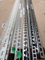 Close view of various aluminum and vinyl tile edge trims showing perforated design and materials