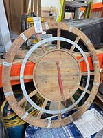Front view of large rustic wall clock showing wood and metal construction