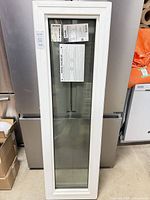 Full view of the white vinyl fixed window insert leaning against appliance