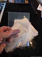 Stack of clear soft plastic sleeves held in hand showing size and transparency