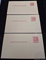 Three unused beige USPS pre-stamped postcards laid flat