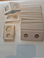 Stack of nickel-size cardboard flips, several loose mixed-size flips, clear plastic two-coin case