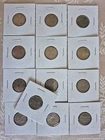 Group shot of 13 sixpence coins in cardboard flips
