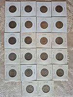 Front view of 22 one shilling coins in individual cardboard flips