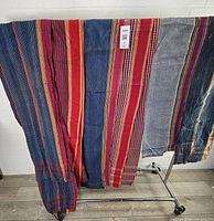 Front view of multiple striped cotton saris draped over rack