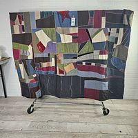 Full view of quilt hanging on rack showing size and overall patchwork design