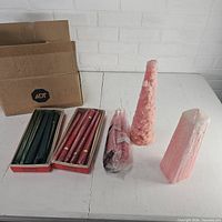 Boxes of green and red taper candles, two pink pillar candles, bagged pink tapers