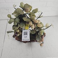 Front view of carved stone grapevine on wood stand with lot tag visible