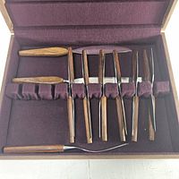 open box showing nine knives in fitted burgundy felt slots
