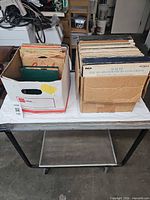 Two boxes of assorted records on table