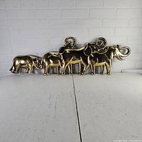 Five metallic gold elephant plaques arranged in a row