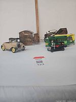 Group showing beige car, black car, green cable car, two wooden music boxes, brown car partly visible