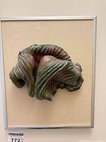 Front view of framed 3D metal art showing abstract folded form