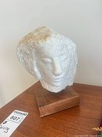 Front view of stone head sculpture on wood base