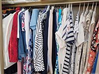 Closet rod with approximately two dozen garments including jackets, dresses, tops and pants