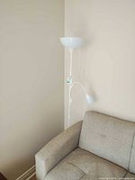 Full view of white floor lamp behind sofa