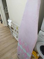 Ironing board front view beside drying rack