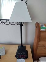 Lamp with white shade and Timex clock radio on bedside table