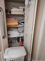 Closet shelves showing towels, linens, cleaning supplies and hamper