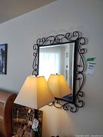 Full view of mirror on wall, showing metal scroll frame