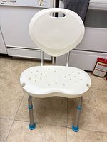 Front view of white AquaSense shower chair showing seat, legs, and blue feet