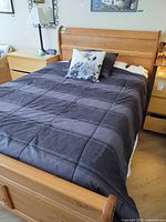 Full view of double wood sleigh bed with bedding and mattress