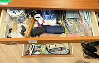 Open drawer showing umbrellas, masks, ceramic jar, power bars, Coleman pump box, batteries, hangers, hairbrush