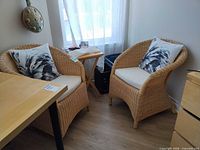 Both wicker chairs positioned in corner with cushions and pillows visible