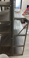 Front view of both metal shelving units showing five shelves each and rust spots