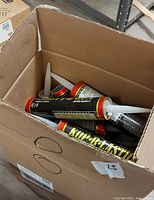 Cardboard box containing multiple unopened caulk tubes