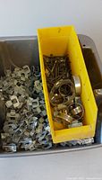 Galvanized roof clips and yellow bin with screws and hose clamps
