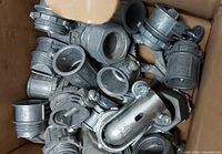 Box filled with various metal conduit connectors