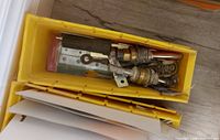 Yellow bin with brass valves, metal plate, misc small hardware