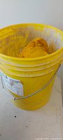 Yellow plastic bucket with hard hat partially visible inside