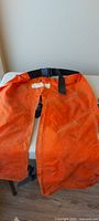 Front of orange nylon chaps with waist buckle