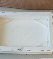 Top view of one white vinyl mounting block showing recessed center and nail flange